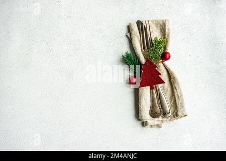 Tovagliolo da tavolo con posate per la cena di Natale su un tavolo di cemento su sfondo bianco Foto Stock