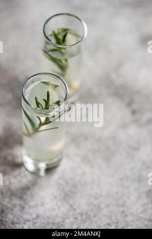 Glassses di vodka rosmarino servito su un tavolo di cemento Foto Stock