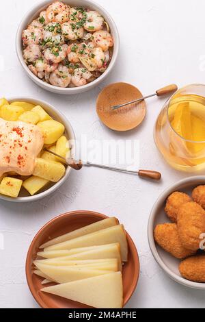 Da sopra assortite tapas spagnole tradizionali servite su ciotole su sfondo bianco tavolo Foto Stock