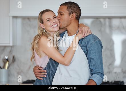 Amore, interracial e coppia bacio in cucina, felicità e amare insieme per il rapporto. Romanticismo, uomo e donna con abbraccio, bacio e. Foto Stock