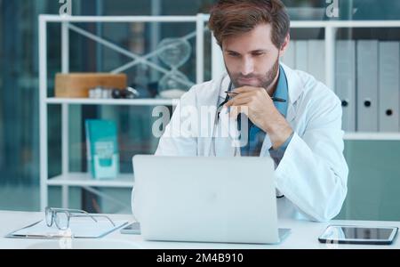 Dottore, scienziato e laptop con un uomo che legge e pensa mentre fa ricerca medica su database o analisi dei dati alla scrivania. Operatore sanitario con Foto Stock