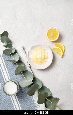 Sale marino giallo biologico con limone, candela e ramificazione di eucalipto su sfondo bianco. Il concetto di spa e benessere. Vista dall'alto e copia Foto Stock