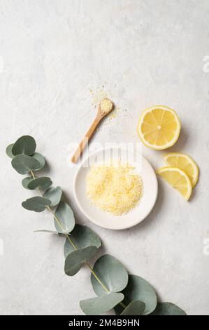 Sale marino giallo biologico con limone e ramificazione di eucalipto su fondo bianco testurizzato. Il concetto di spa e benessere. Vista dall'alto e spazio di copia. Foto Stock