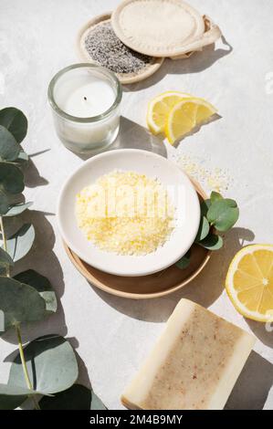 Sale marino giallo biologico con limone, sapone, spugna e ramificazione di eucalipto su fondo bianco. Il concetto di spa e benessere. Foto Stock