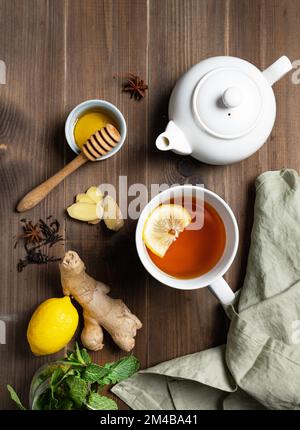 Sistema immunitario booster - tè con zenzero, miele, limone, menta e spezie su uno sfondo di legno scuro. Il concetto di cibo sano. Vista dall'alto. Foto Stock