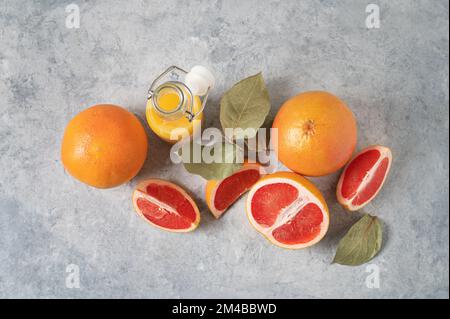 disposizione di succosi pompelmi rossi e succo in bottiglia su sfondo blu. Concetto di cibo sano e dieta. Vista dall'alto e spazio di copia. Foto Stock