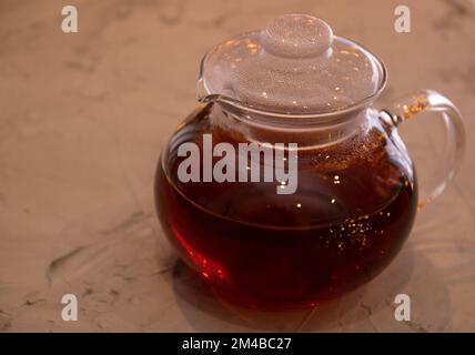 foto del tè in una teiera di vetro su sfondo grigio irregolare Foto Stock