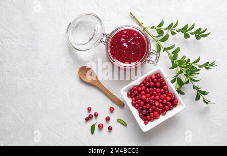 Concetto piatto con marmellata di mirtilli fatti in casa e cowberry foresta in ciotola su sfondo bianco. Vista dall'alto e immagine dello spazio di copia Foto Stock