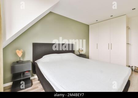 una camera da letto con pareti verdi e pavimento in legno bianco la camera  ha un letto grande, due comodini e una tv a schermo piatto Foto stock -  Alamy
