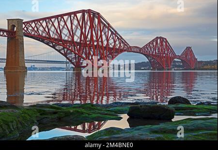 South Queensferry. Edimburgo, Scozia, Regno Unito. 20th dicembre 2022. Nuvoloso all'alba, ma il sole apparve poco dopo per lanciare una calda luce mattutina sul Forth Rail Bridge. Temperatura un più mite 6 gradi centigradi dalle settimane precedenti temperature di congelamento ma ancora pavimenti ghiacciati nel Queensferry del Sud. Credit: ArchWhite/alamylive news. Foto Stock