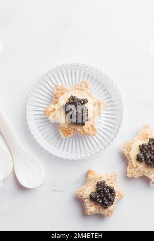 Antipasti neri al caviale stelle del pane con burro su sfondo bianco vista dall'alto verticale Foto Stock