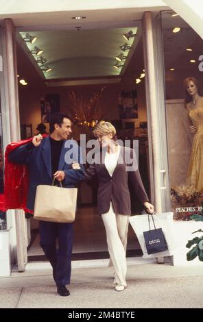 Coppia giovane e ben vestita che cammina con le borse dello shopping Foto Stock