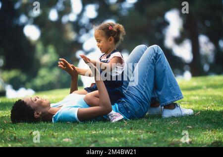 Madre e bambina afroamericana che giocano in erba Foto Stock