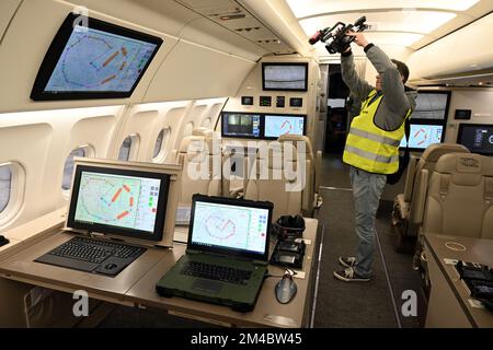 Colonia, Germania. 20th Dec, 2022. Un cameraman filma computer a bordo dell'Airbus A319 OH. L'aeromobile sarà utilizzato in futuro per dare vita al "Trattato sui cieli aperti (OH)". In questo trattato del 1992, gli stati membri si impegnano ad avere voli di osservazione effettuati sul loro territorio nazionale da altri stati contraenti. Credit: Federico Gambarini/dpa/Alamy Live News Foto Stock