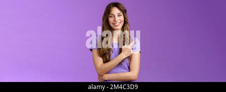 Allegro intelligente sicuro assertivo capelli ricci caucasici femmina condividere link puntando indice dita in alto a sinistra sorridendo ampiamente dare consigli cosa Foto Stock