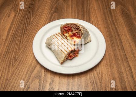 Un durum di fusione con carne di agnello, peperoni e formaggio fuso su un piatto bianco Foto Stock