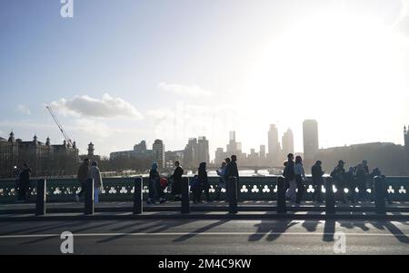 La gente cammina lungo il Westminster Bridge, nel centro di Londra. Neve e ghiaccio hanno attraversato alcune parti del Regno Unito, con condizioni di freddo viticolo impostato per continuare per giorni. Data immagine: Martedì 20 dicembre 2022. Foto Stock
