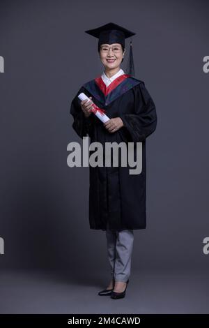 Allievo cinese anziano che festeggiava per la laurea Foto Stock