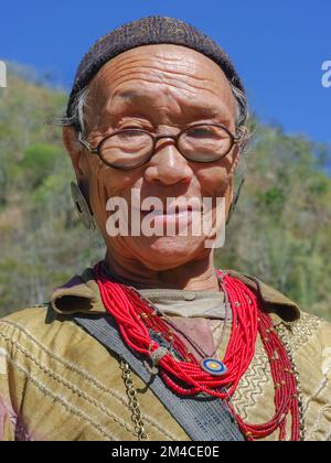 Raga, Arunachal Pradesh, India - 11 20 2013 : Ritratto all'aperto della vecchia tribù Nyishi con occhiali che indossano orecchini tradizionali e collane rosse Foto Stock