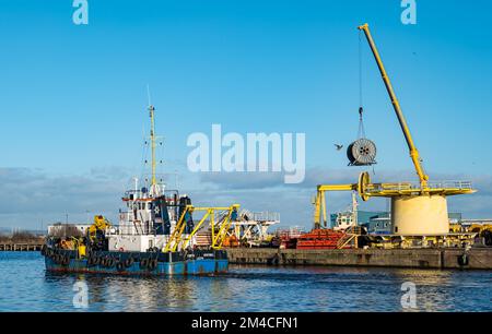 La nave di servizio Forth Sentinel che draga Leith Harbour con una ruota per cavi di sollevamento con gru sul molo, Edimburgo, Scozia, Regno Unito Foto Stock
