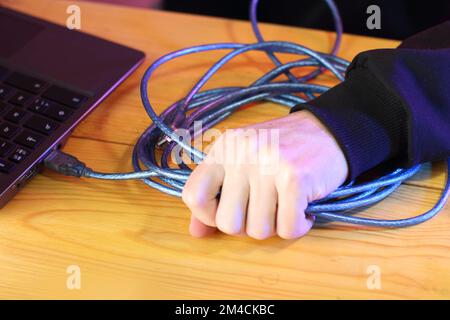 tirare con forza il cavo usb dal computer portatile sul tavolo e sullo sfondo colorato Foto Stock