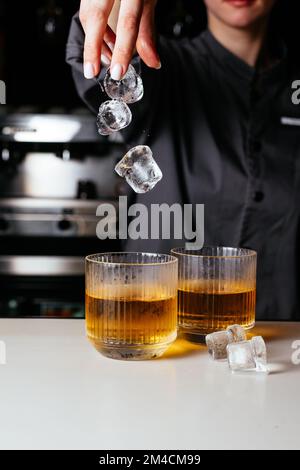 i cubetti di ghiaccio cadono in un bicchiere di whisky Foto Stock