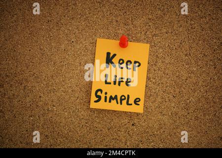 Una nota di carta gialla con le parole Keep Life Simple su di essa fissata a una tavola di sughero. Primo piano. Foto Stock