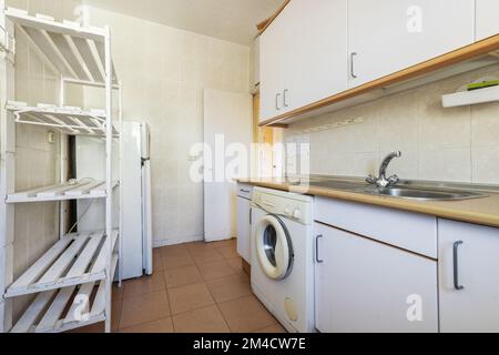 Vecchia cucina con armadi usati e scaffali in legno dipinto di bianco Foto Stock