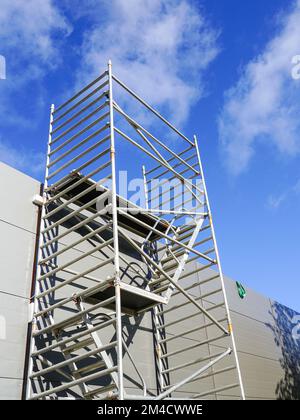 Moderna impalcatura tubolare di metallo multilivello accanto alla facciata a pannelli sandwich di un nuovo edificio Foto Stock
