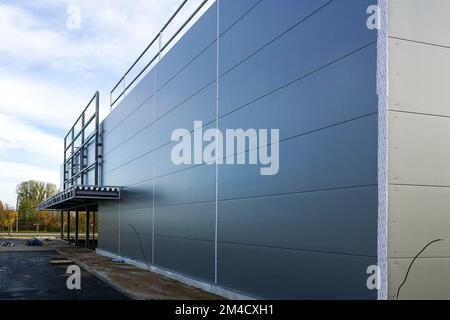 Facciata grigia a pannelli sandwich di un edificio di magazzino incompiuto, sfondo blu cielo Foto Stock