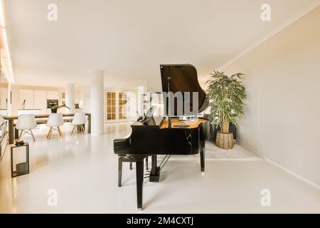 un soggiorno con un pianoforte nel mezzo e una zona pranzo aperta sull'altro lato a destra Foto Stock