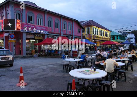 Ipoh, Perak, Malesia - 2012 ottobre: La gente che cena sui tavoli all'esterno di un caffè su una strada fiancheggiata da negozi del patrimonio case nella città vecchia di Ipoh. Foto Stock