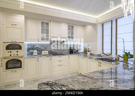 Cucina classica color crema con isola usata come zona pranzo in appartamento monolocale Foto Stock