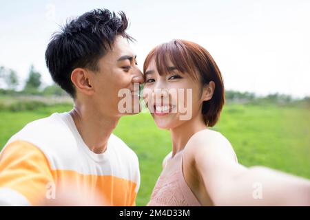 Felice giovane coppia cinese baciare nel parco Foto Stock