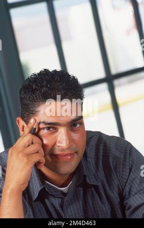 Primo piano di un ragazzo che si appoggia alla mano con la penna e guarda la macchina fotografica Foto Stock