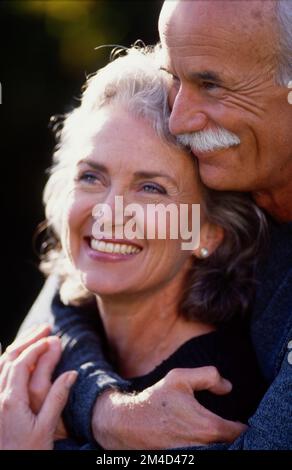 Coppia più anziana che abbraccia con un abbraccio stretto, uomo dietro la donna Foto Stock