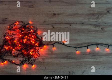 luci rosse di natale aggrovigliate su un tavolo di legno Foto Stock