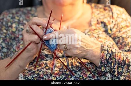 Donna anziana che si inginocchiava e guardava la TV allo stesso tempo Foto Stock