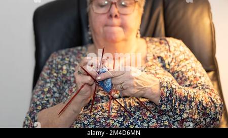 Donna anziana che si inginocchiava e guardava la TV allo stesso tempo Foto Stock