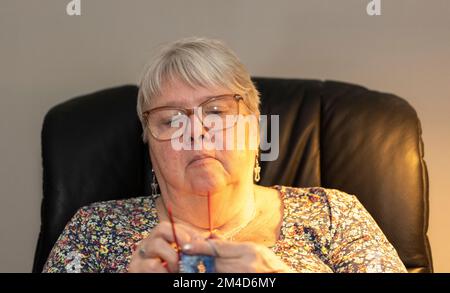 Donna anziana che si inginocchiava e guardava la TV allo stesso tempo Foto Stock