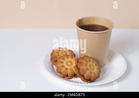 Biscotti e caffè in una tazza usa e getta su un piatto di carta. Cibo da asporto. Piatti biodegradabili Foto Stock