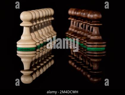 Due linee diagonali opposte di pedine di scacchi in legno con messa a fuoco selettiva isolata sullo sfondo con riflessione trasparente sul pavimento Foto Stock