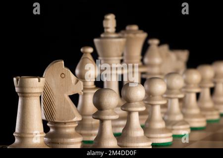 Linea diagonale di scacchi in legno bianco con messa a fuoco selettiva isolata su sfondo scuro Foto Stock