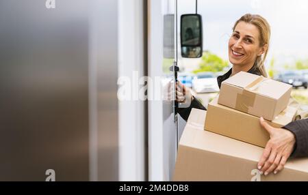 donna sorridente che tiene pacchi davanti a un furgone per consegnarlo a un cliente, con spazio per la copia di un singolo testo Foto Stock