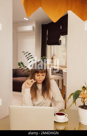Donna ufficio domestico e lavoro a distanza. Una giovane donna d'affari seduta alla scrivania che digita il suo laptop in un ufficio domestico, Foto Stock