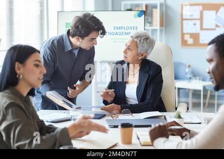 Ritratto di capo donna senior che istruisce il dipendente durante la riunione d'affari in ufficio Foto Stock