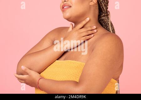 Amore di sé e concetto di accettazione. Donna nera più taglia con perfetta posa della pelle avvolto in asciugamano su sfondo rosa Foto Stock