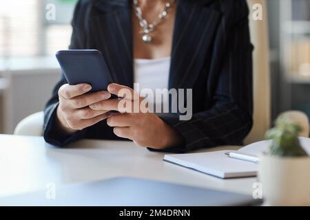 Primo piano di una donna manager utilizzando lo smartphone sul posto di lavoro in ufficio, spazio copia Foto Stock