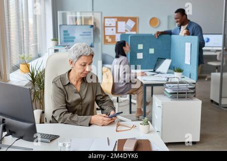 Ritratto di elegante donna d'affari senior che lavora alla scrivania in un ambiente open Office, spazio copia Foto Stock