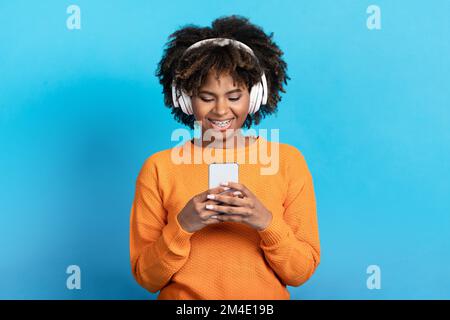 Giovane donna nera sorridente che ascolta musica in cuffia Foto Stock